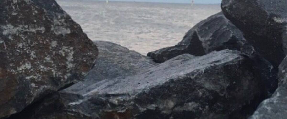 A rocky shoreline with a sunset over the ocean.