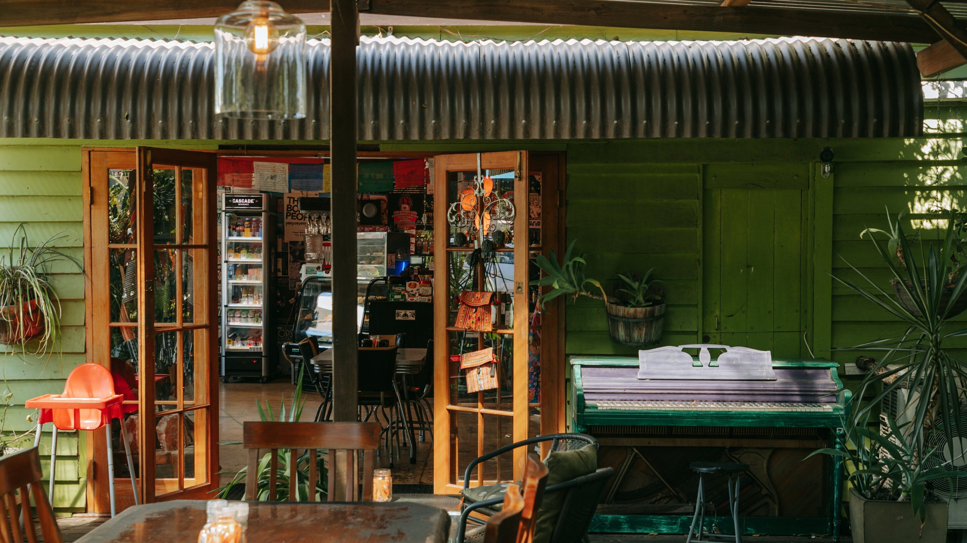Una tienda rústica con estantes de madera, un piano y diversas plantas.