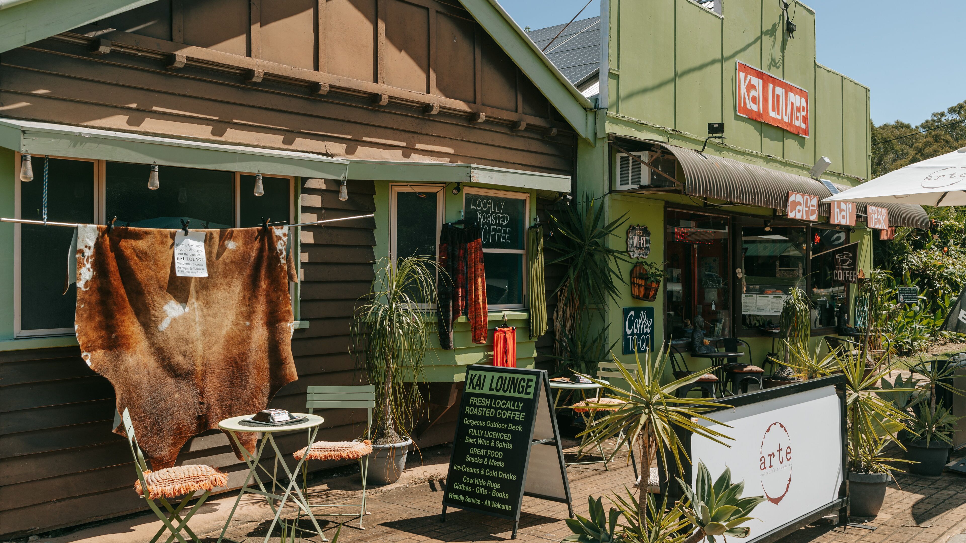 A cafe with a sign reading "Kal Lounge" and a signboard advertising "Coffee to Go".