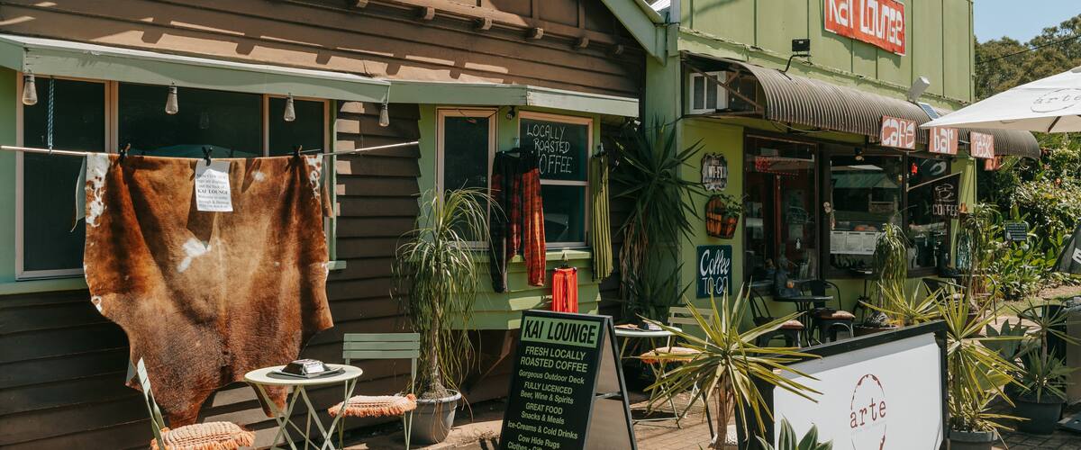 A cafe with a sign reading "Kal Lounge" and a signboard advertising "Coffee to Go".