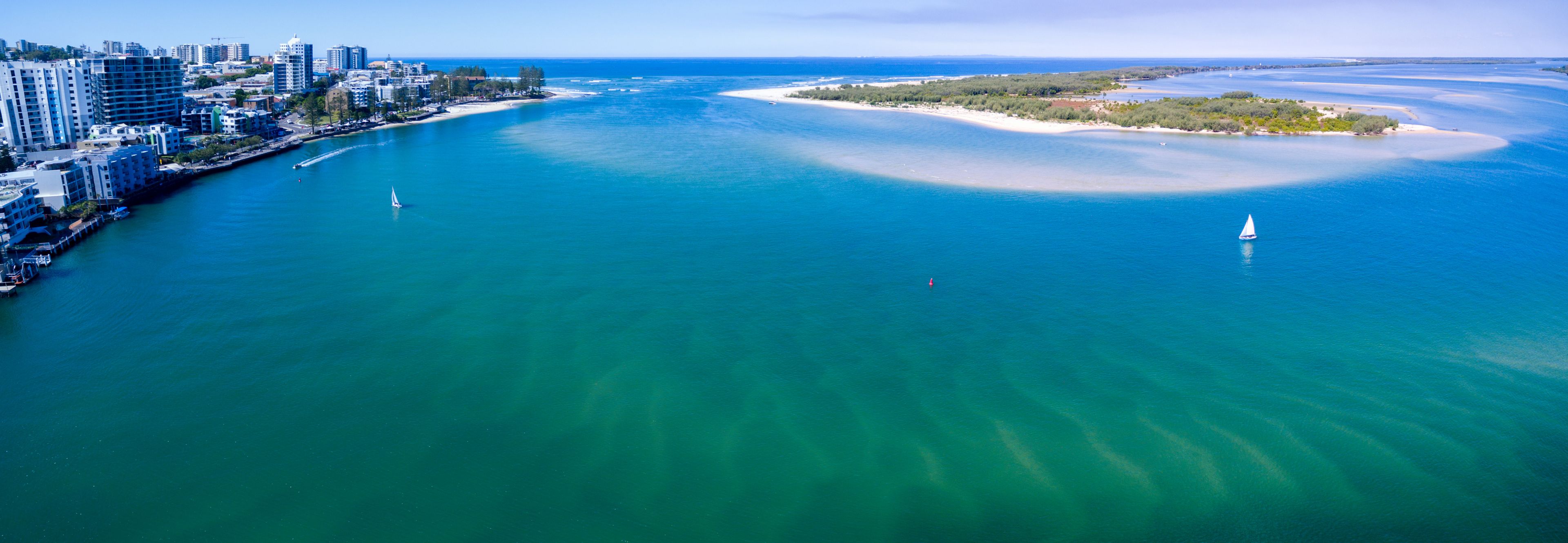 A coastal city with a marina, a sandy beach, and a clear blue sea.