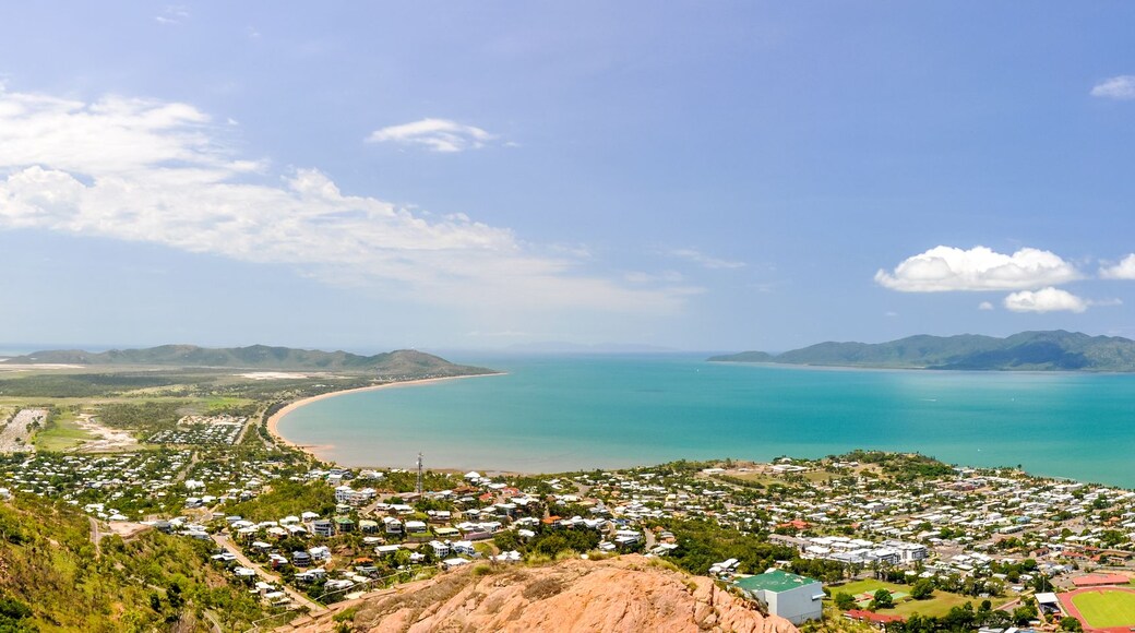 A coastal town with a bay, mountains in the background, and a clear sky.