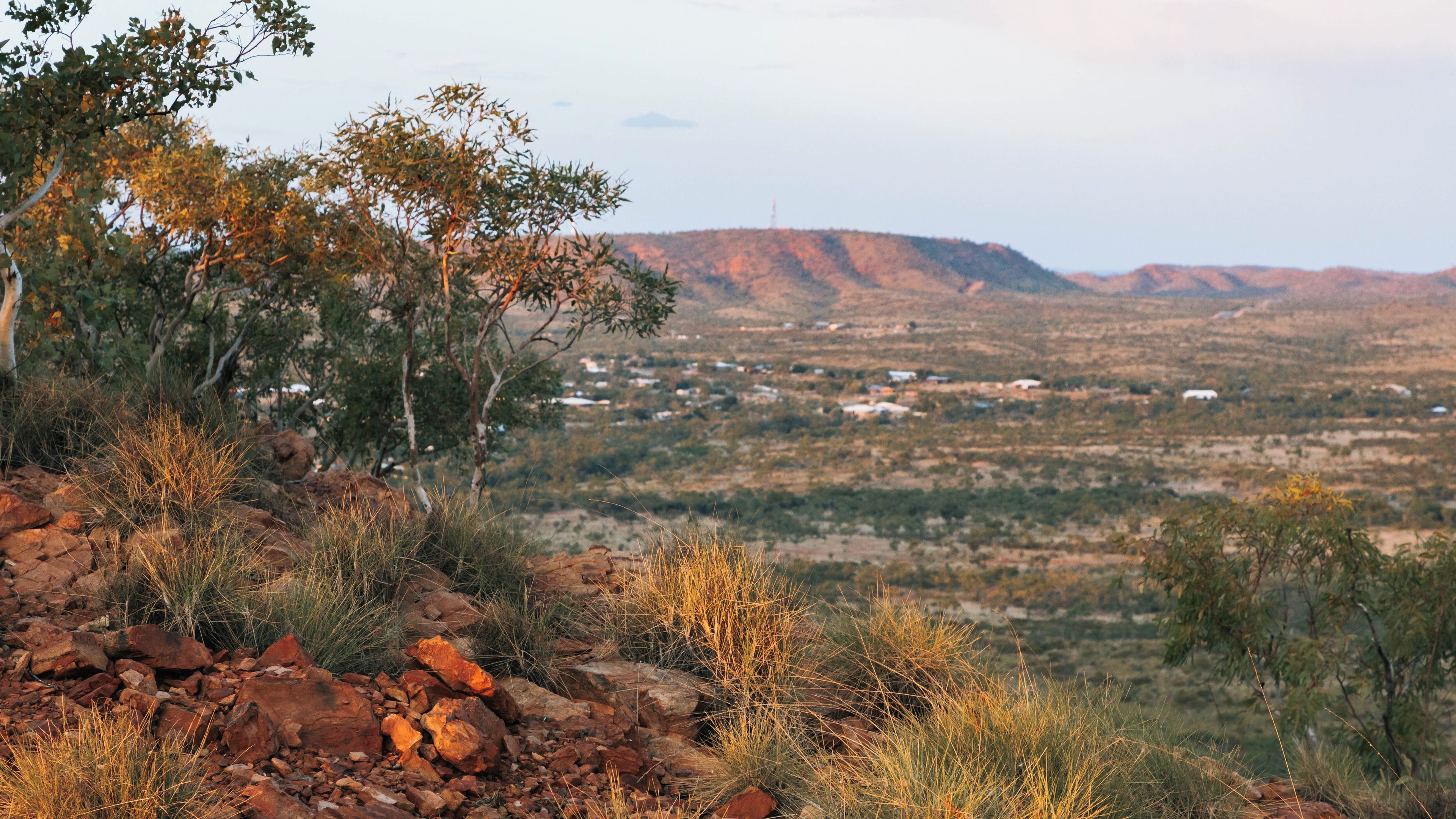 A rugged landscape with rocky outcrops, sparse vegetation, and a distant town nestled in the valley.