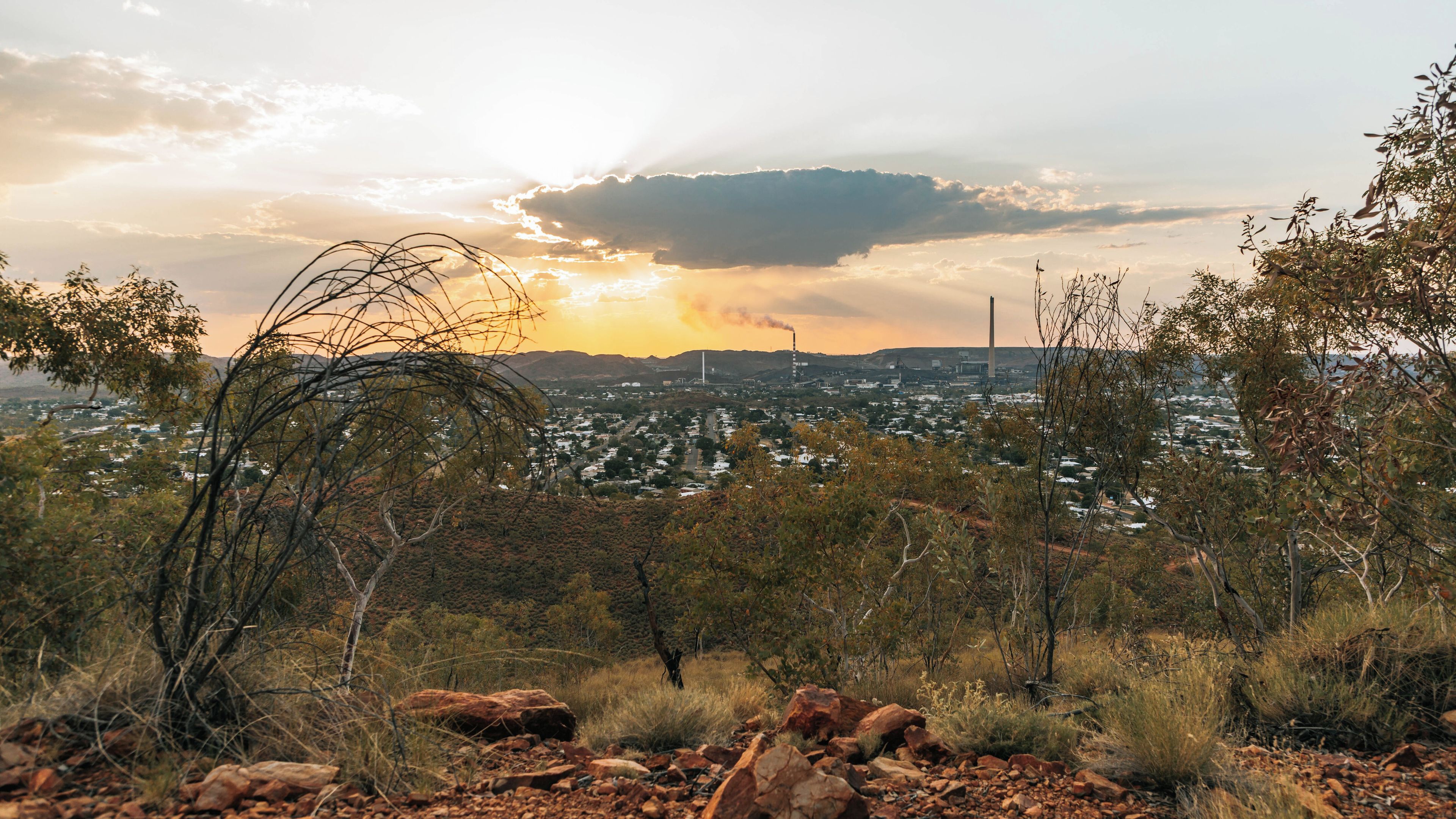 A landscape with a city in the distance, surrounded by rocky terrain and sparse vegetation.