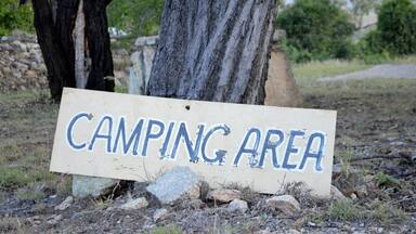 A sign that reads "CAMPING AREA" placed on a rock.