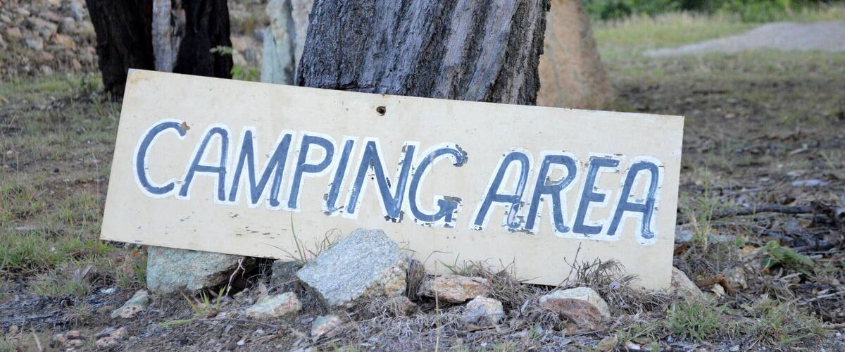 A sign that reads "CAMPING AREA" placed on a rock.