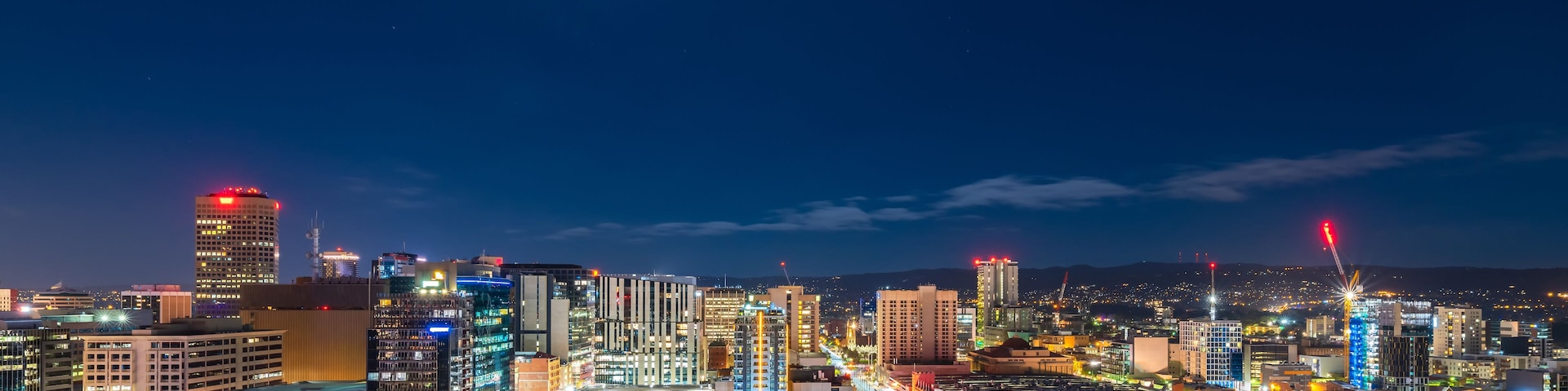 Un paisaje urbano nocturno con edificios iluminados y una calle concurrida.
