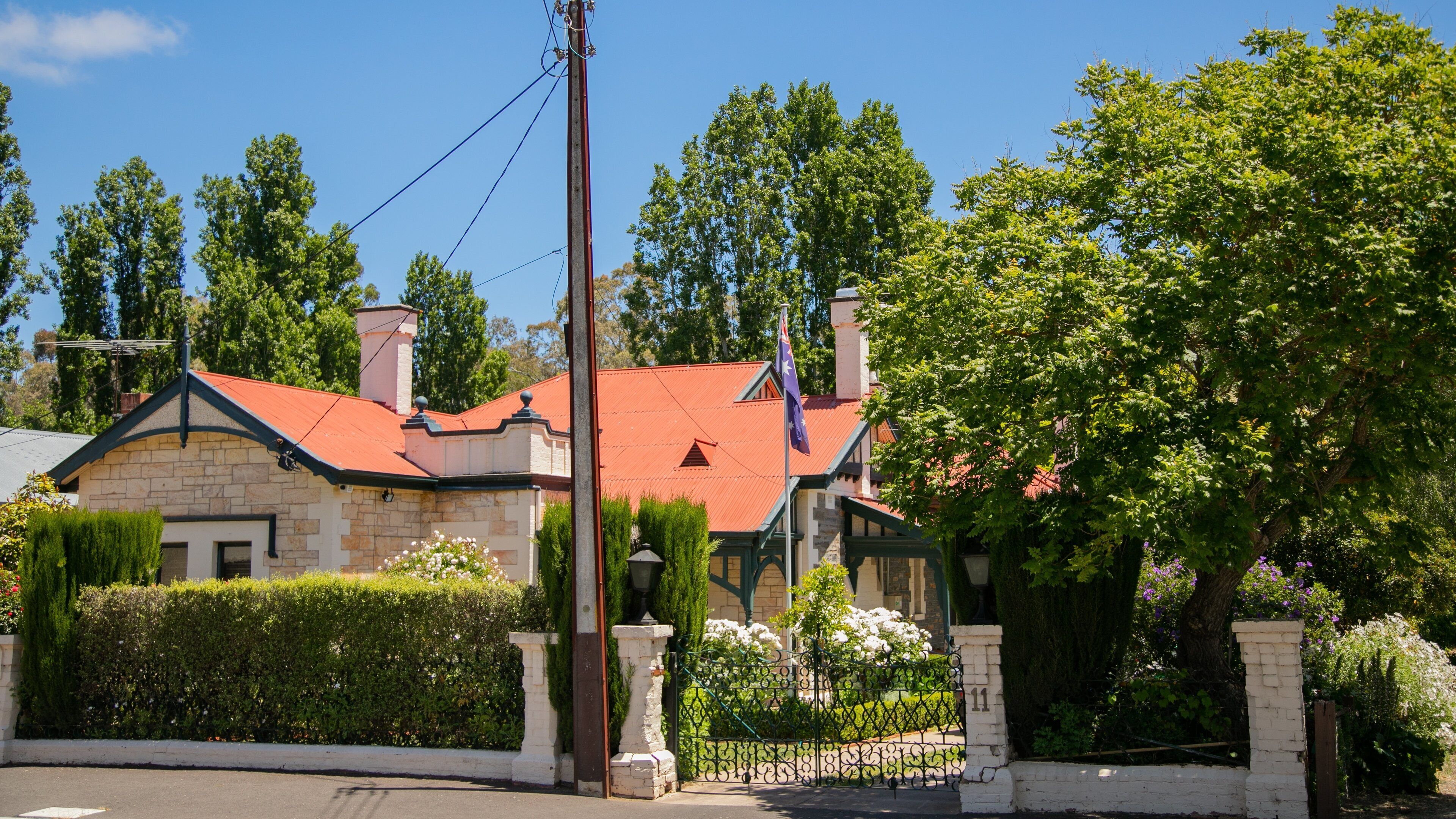 A stone house with a red roof, surrounded by lush greenery and a well-maintained garden.