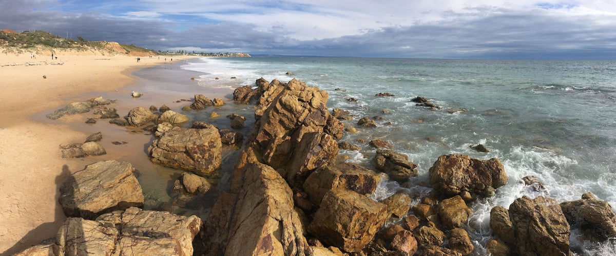 A rocky shoreline with waves crashing onto the beach.