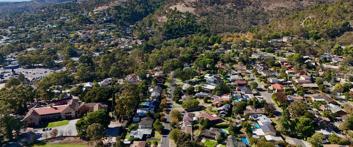 A residential area with houses, streets, and a hilly landscape in the background.