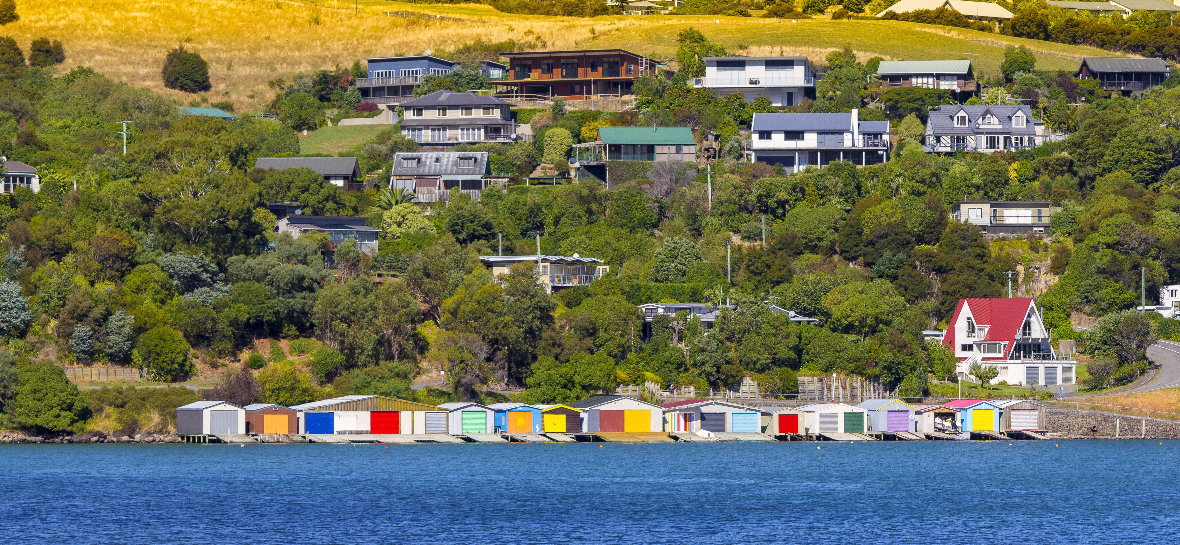 A coastal village with colorful boathouses and houses on a hillside.