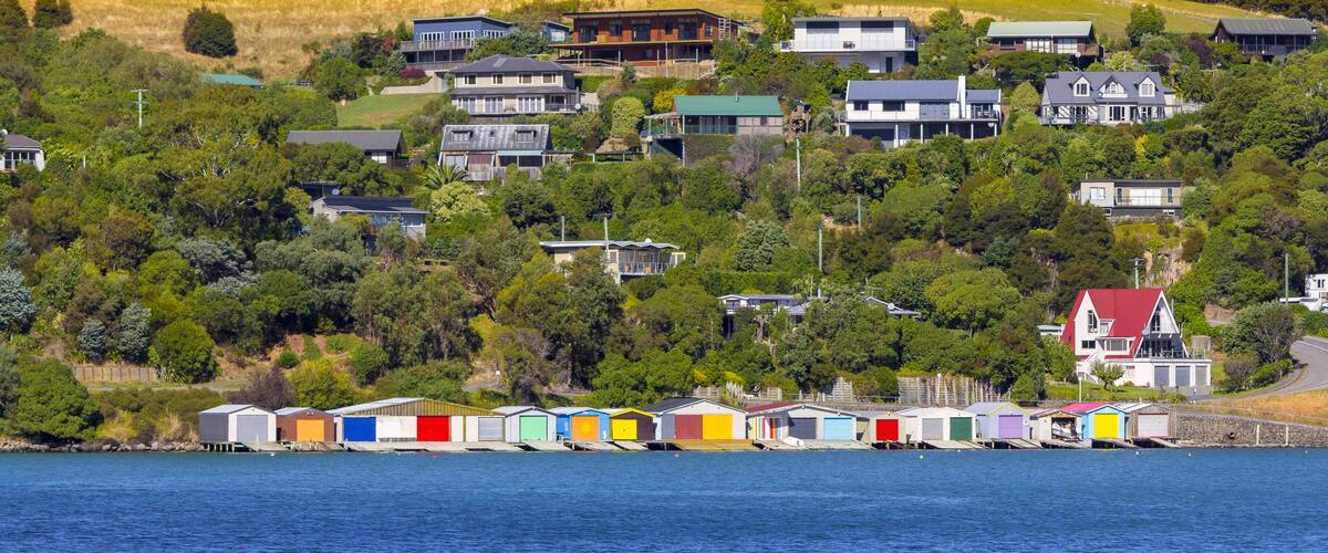 A coastal village with colorful boathouses and houses on a hillside.