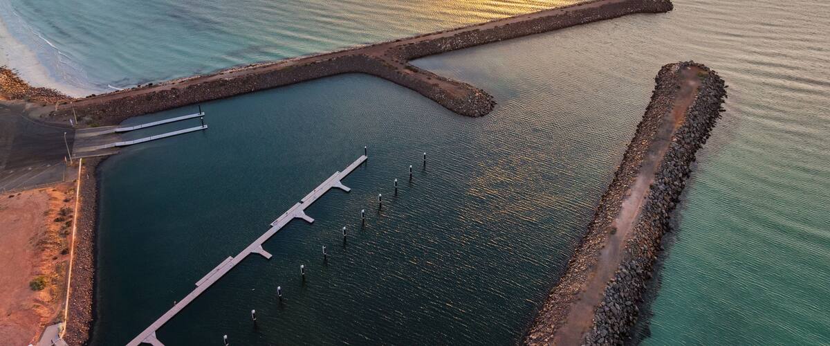 Sunset over rock breakwaters in a blue sea at dusk