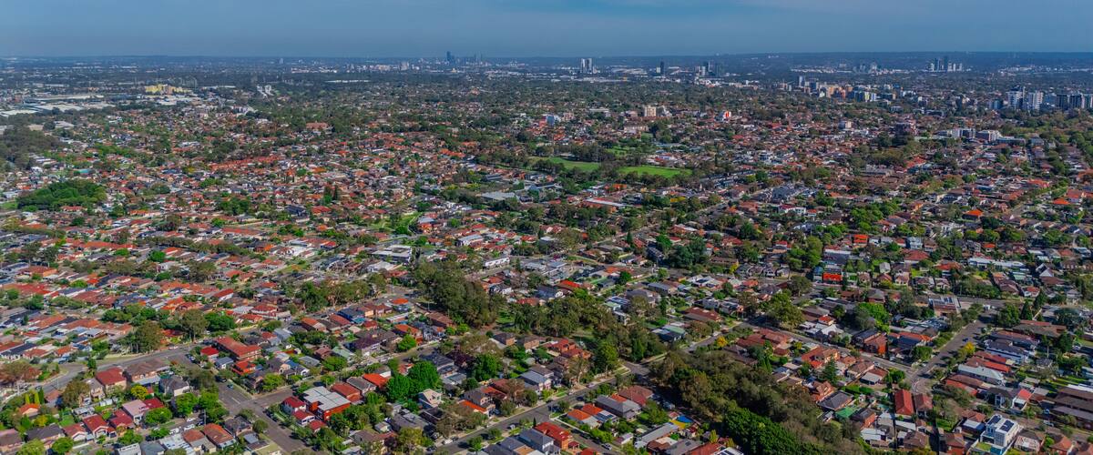 A densely populated urban area with numerous residential buildings and a distant city skyline.