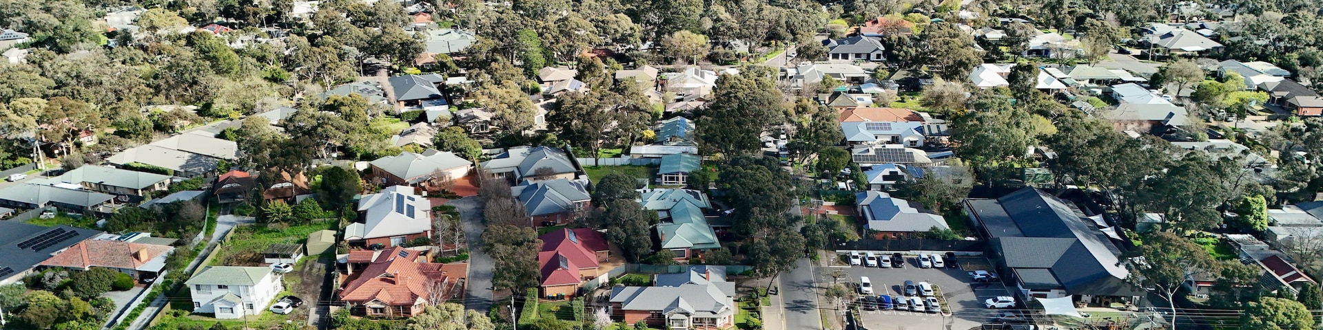 An aerial view of a residential area with houses, roads, and a distant cityscape.
