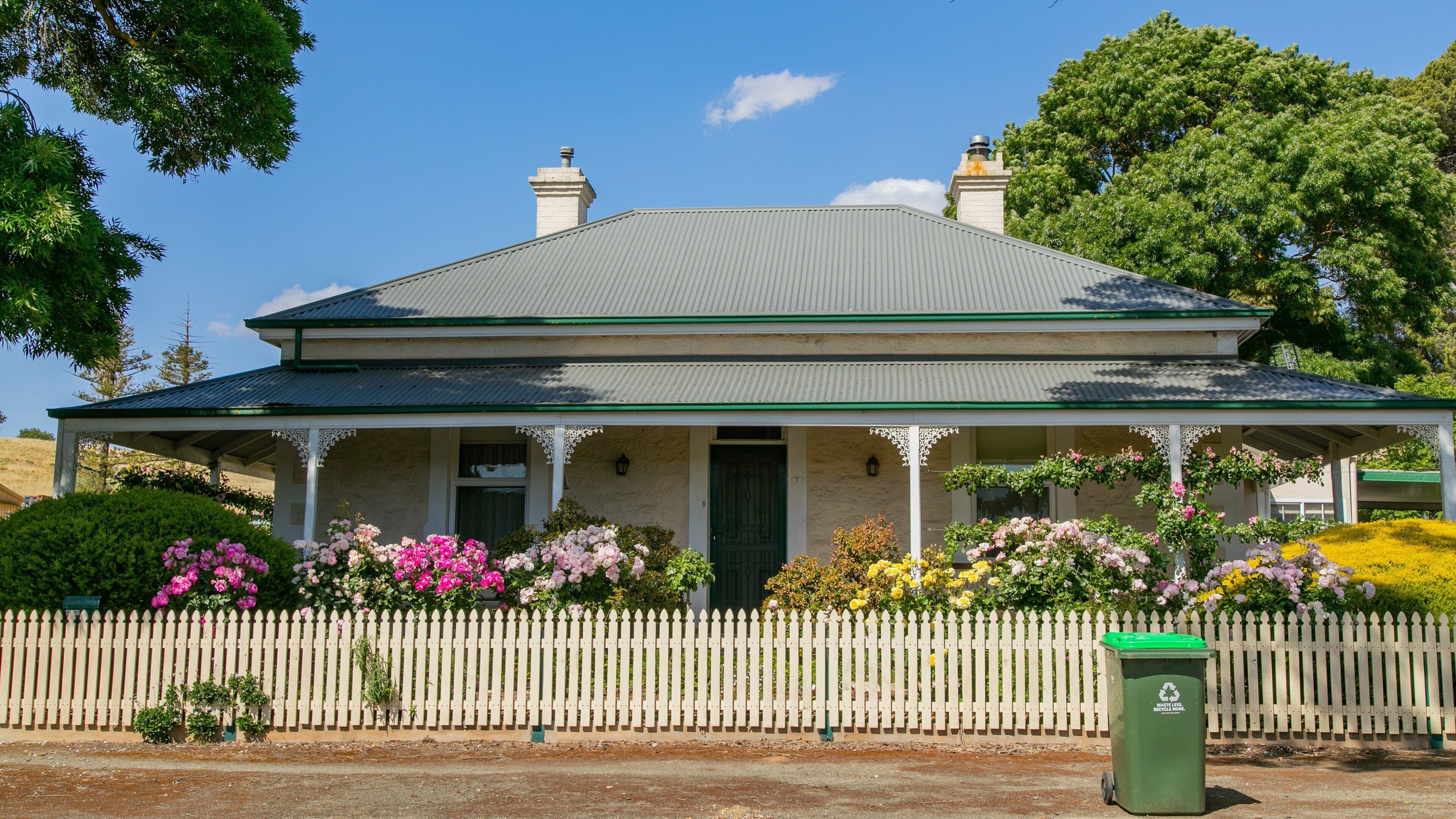 A two-story house with a green roof and white picket fence.