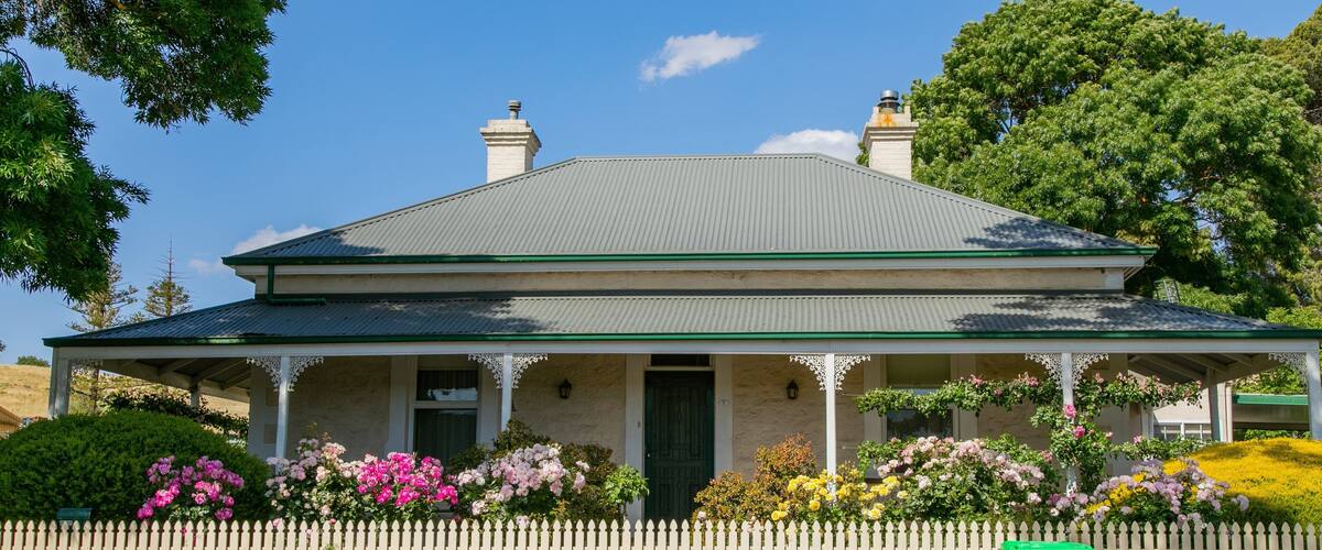 A two-story house with a green roof and white picket fence.