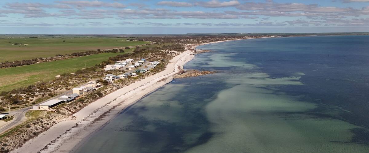 A coastal town with a beach, houses, and clear blue waters.
