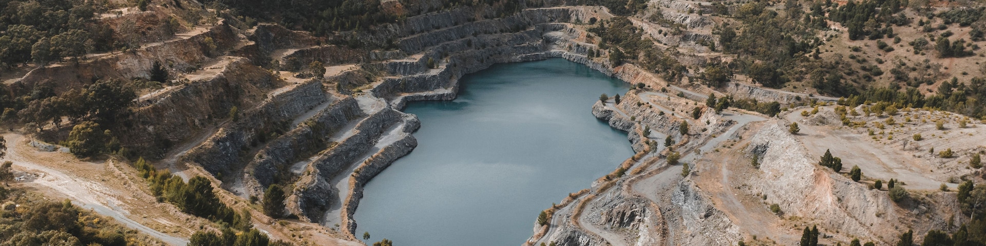 Une vaste carrière circulaire, dont les bords sont aménagés en terrasses et qui contient un bassin d’eau au centre.