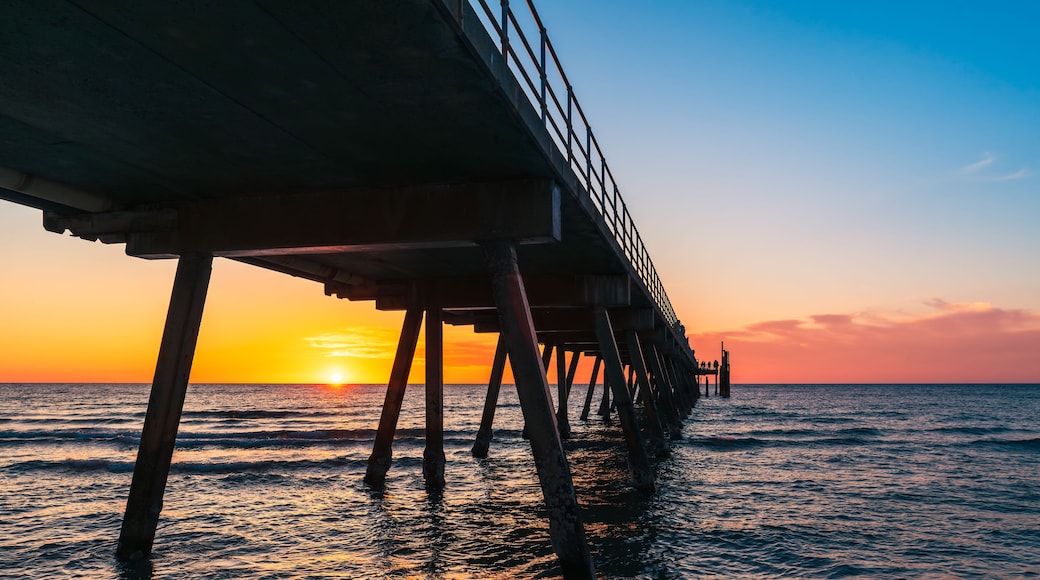 A pier extending into the ocean at sunset.