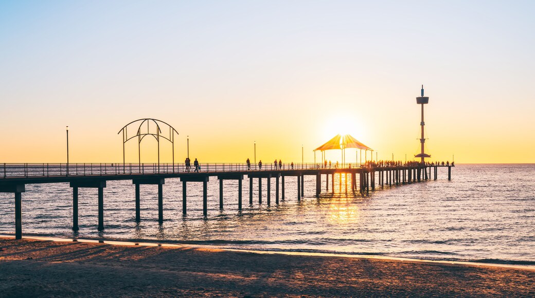 Silhouettes of people walking on Brighton Jetty during sunset