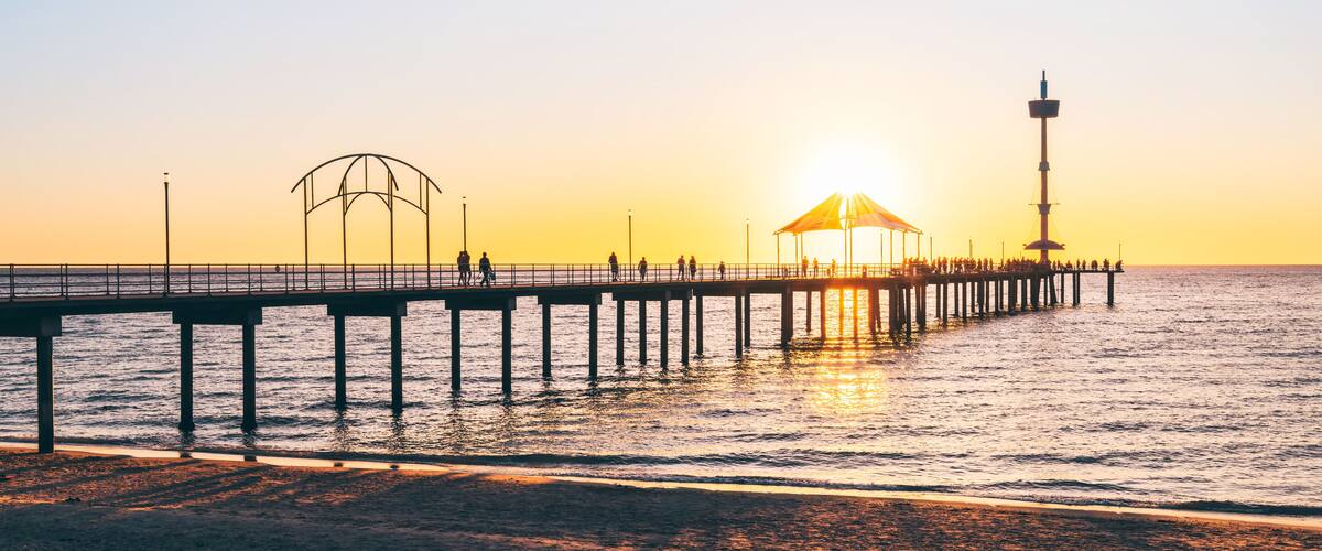 Silhouettes of people walking on Brighton Jetty during sunset