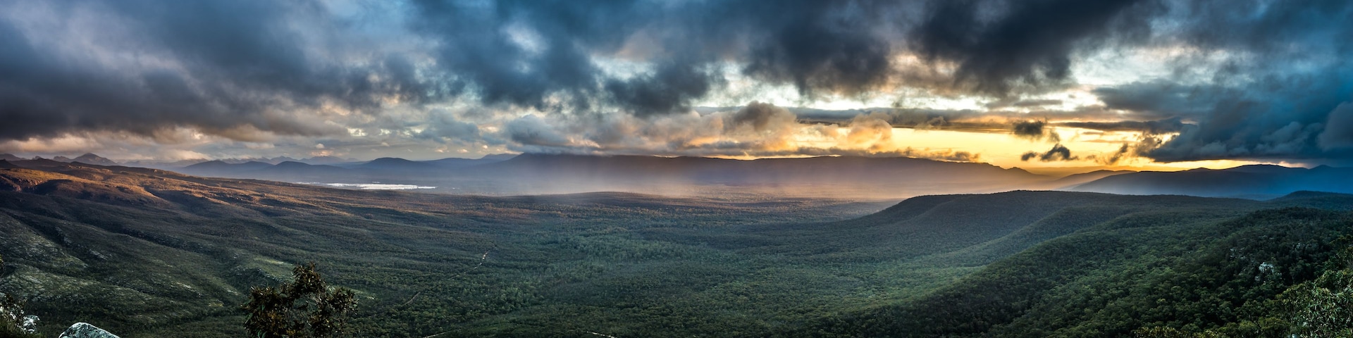 Un paisaje montañoso con cielo nublado y un atardecer.