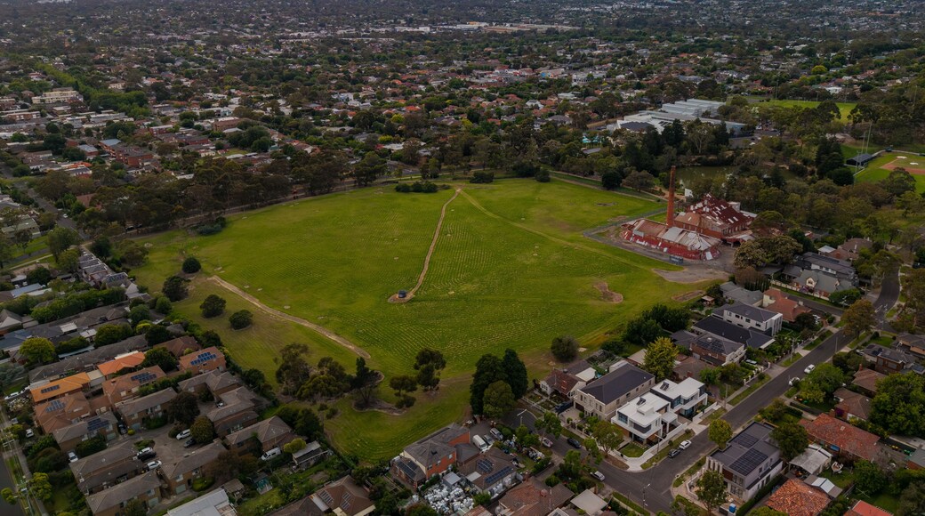 Aerial View of Box Hill Brickworks and Expansive Parkland Surrounded by Residential Suburbs Under a Warm, Cloudy Sky at Dusk