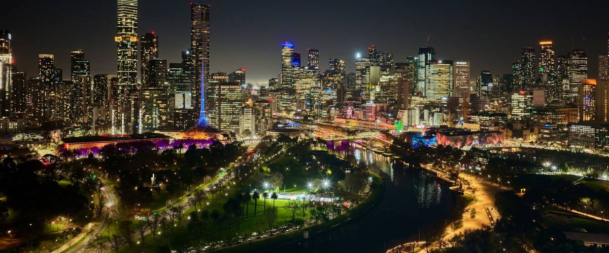 Melbourne, Victoria, Australia by night– 4K aerial drone view of Melbourne CBD skyline, Yarra River, Arts Centre, Flinders Street Station and illuminated skyscrapers at sunset twilight