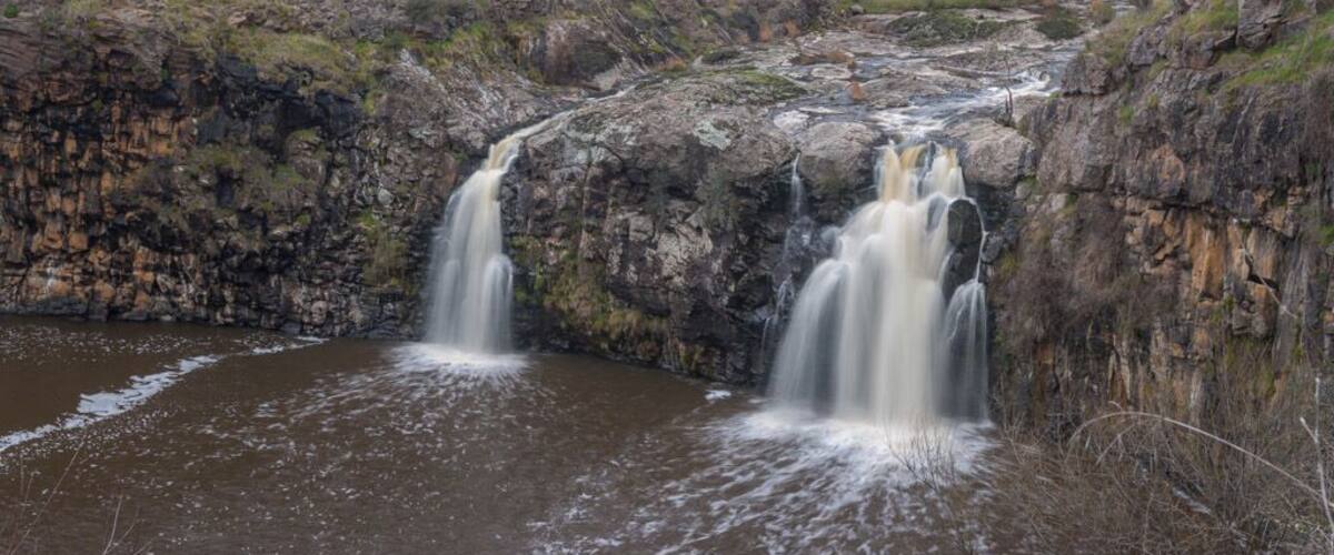 A waterfall cascading over rocky cliffs into a calm pool.