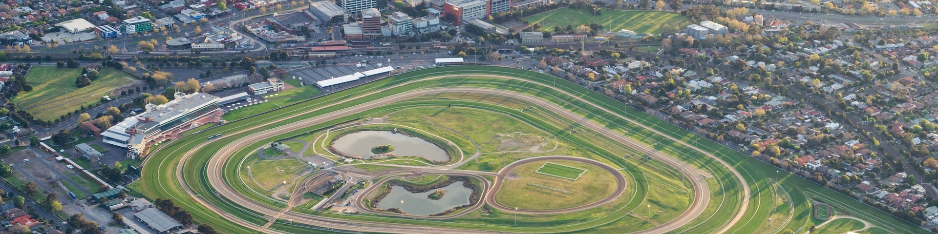Une vue aérienne d’une ville avec un grand stade de forme ovale, entouré de zones résidentielles et de routes.