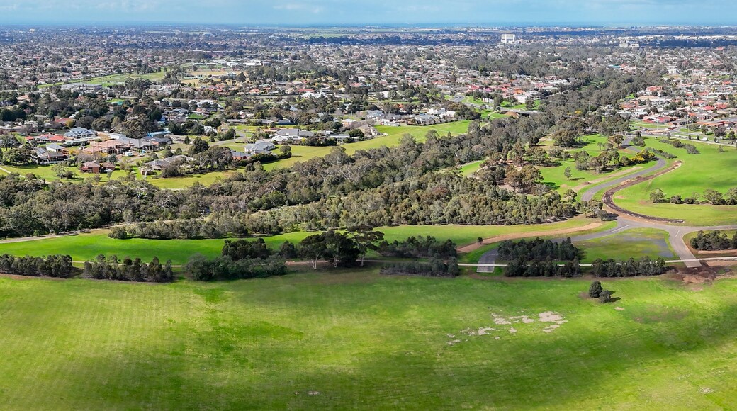 Una vista aerea di una città con zone residenziali, campi verdi e un parco.