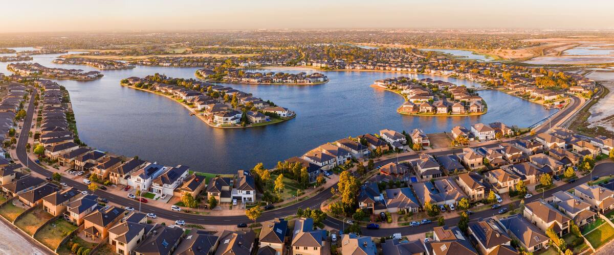 A residential area with houses arranged around a central water body, connected by roads.