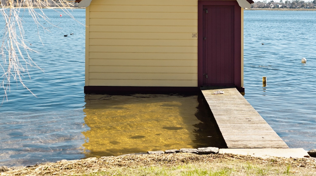 A small, yellow boathouse with a purple door, number 14, on a dock extending into a calm lake.
