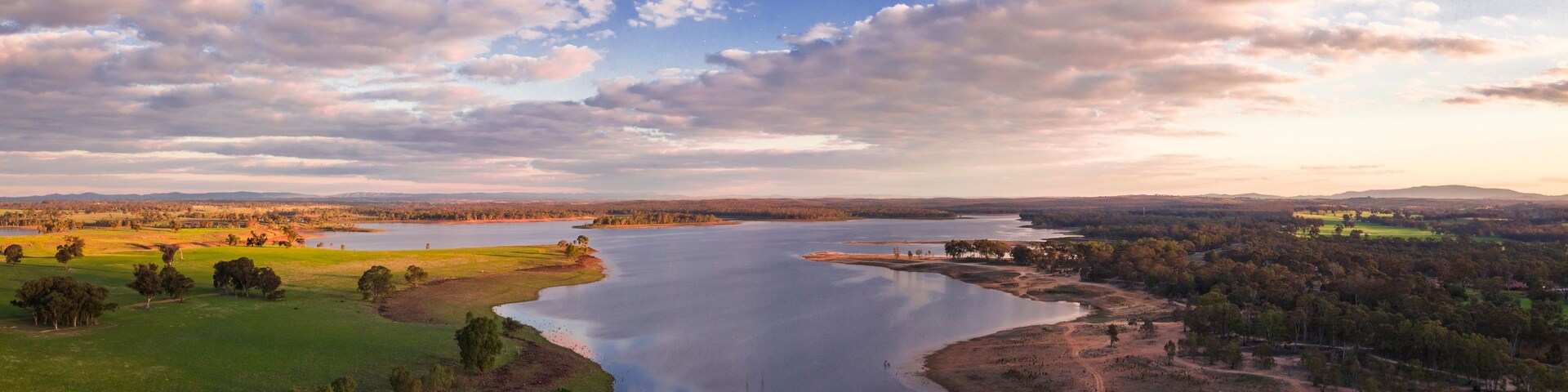 Un gran lago rodeado de campos y árboles, con un cielo nublado.