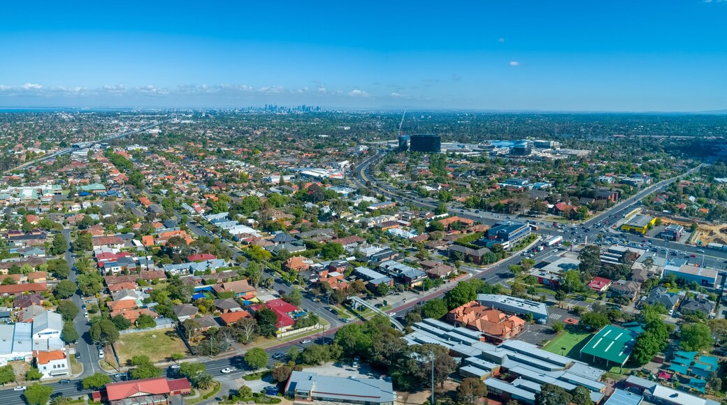Wide aerial panorama of Oakleigh suburb with Melbourne CBD high rise buildings in the distance