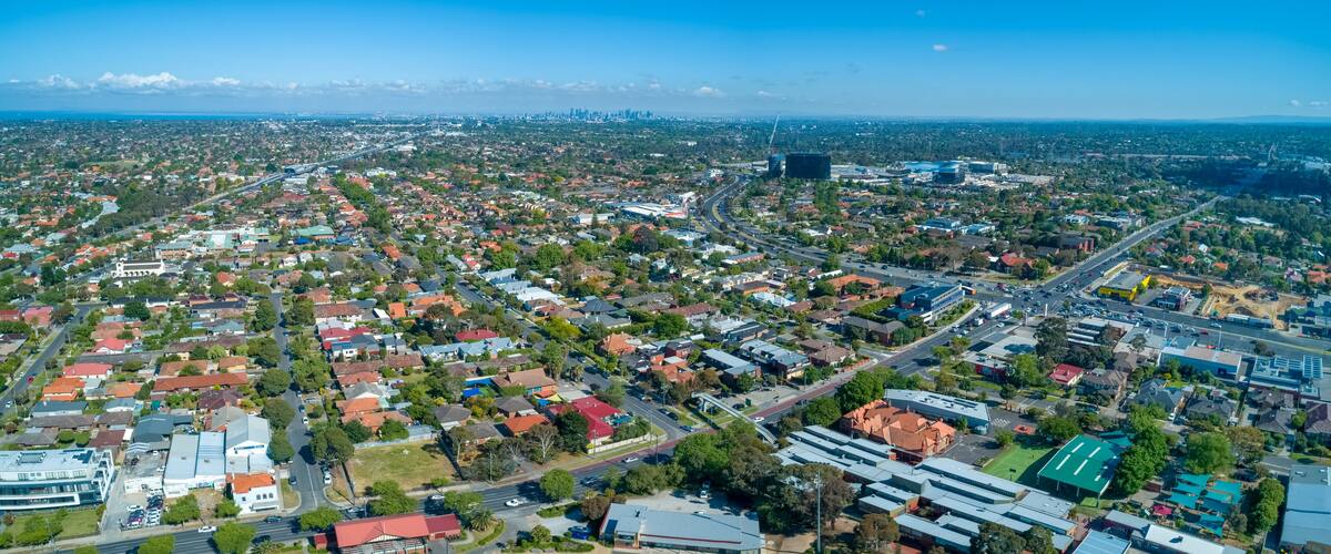 Wide aerial panorama of Oakleigh suburb with Melbourne CBD high rise buildings in the distance