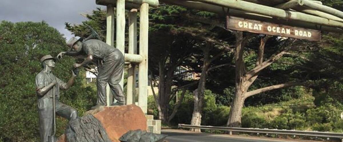 A statue of a man and woman, a wooden structure, and a road sign reading "Great Ocean Road".