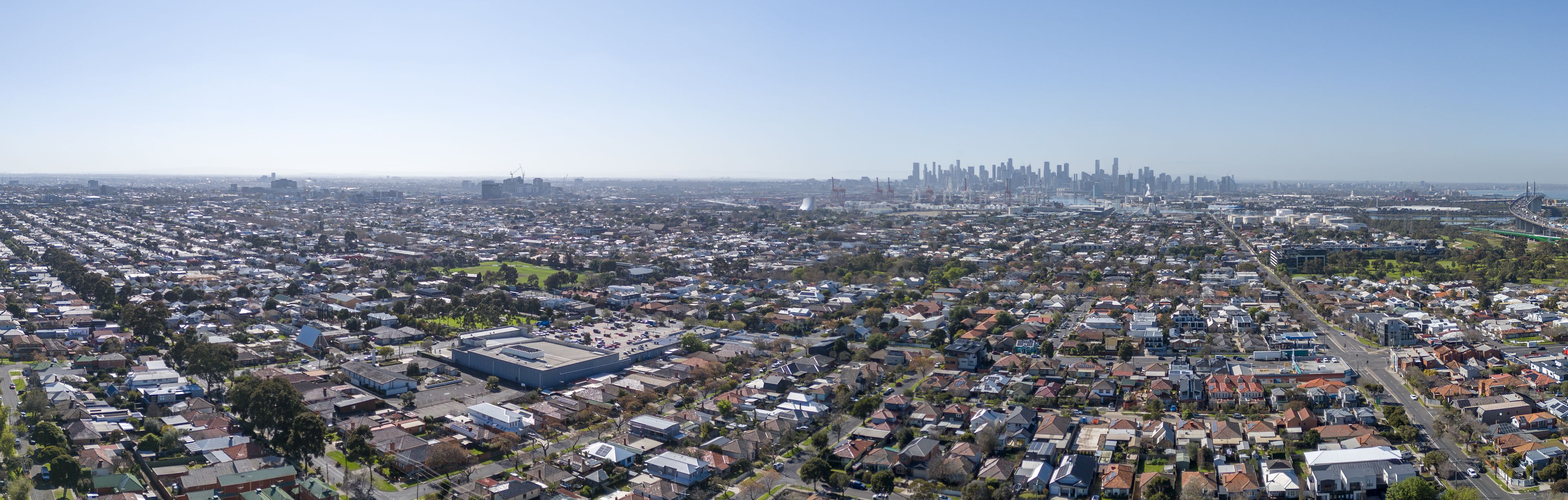 A densely populated urban area with a prominent industrial building and a distant city skyline.