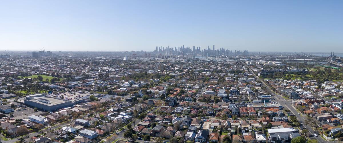 A densely populated urban area with a prominent industrial building and a distant city skyline.