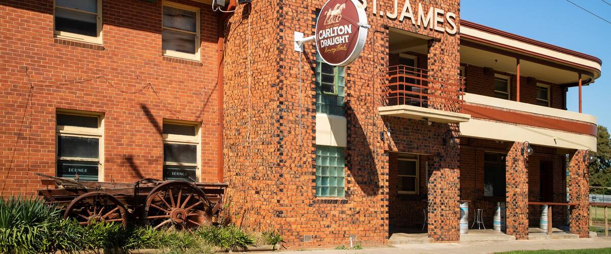 A historic hotel with a large sign reading "HOTEL ST. JAMES" and a vintage car parked in front.