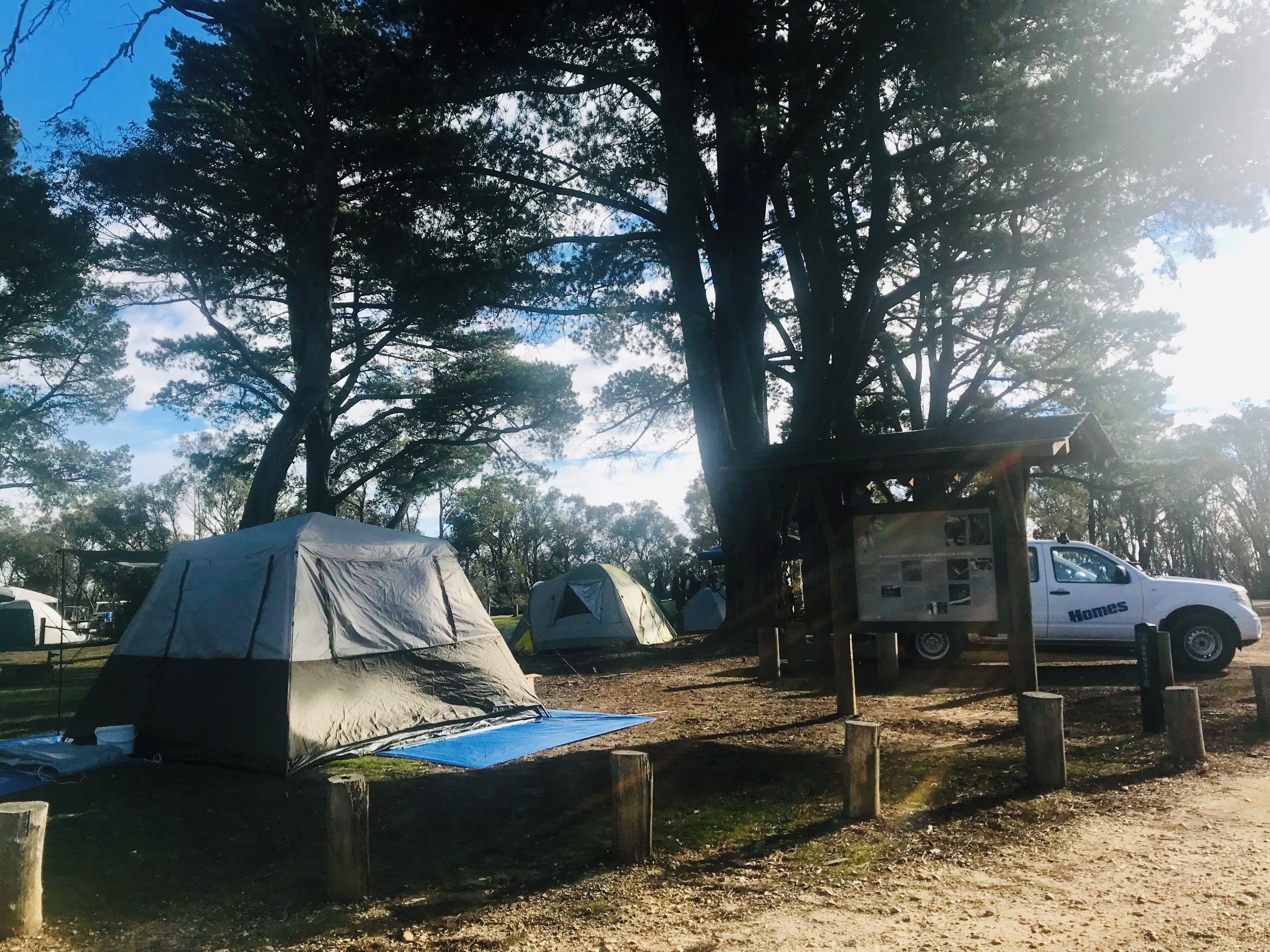 A campsite with tents, a truck, and a wooden structure.