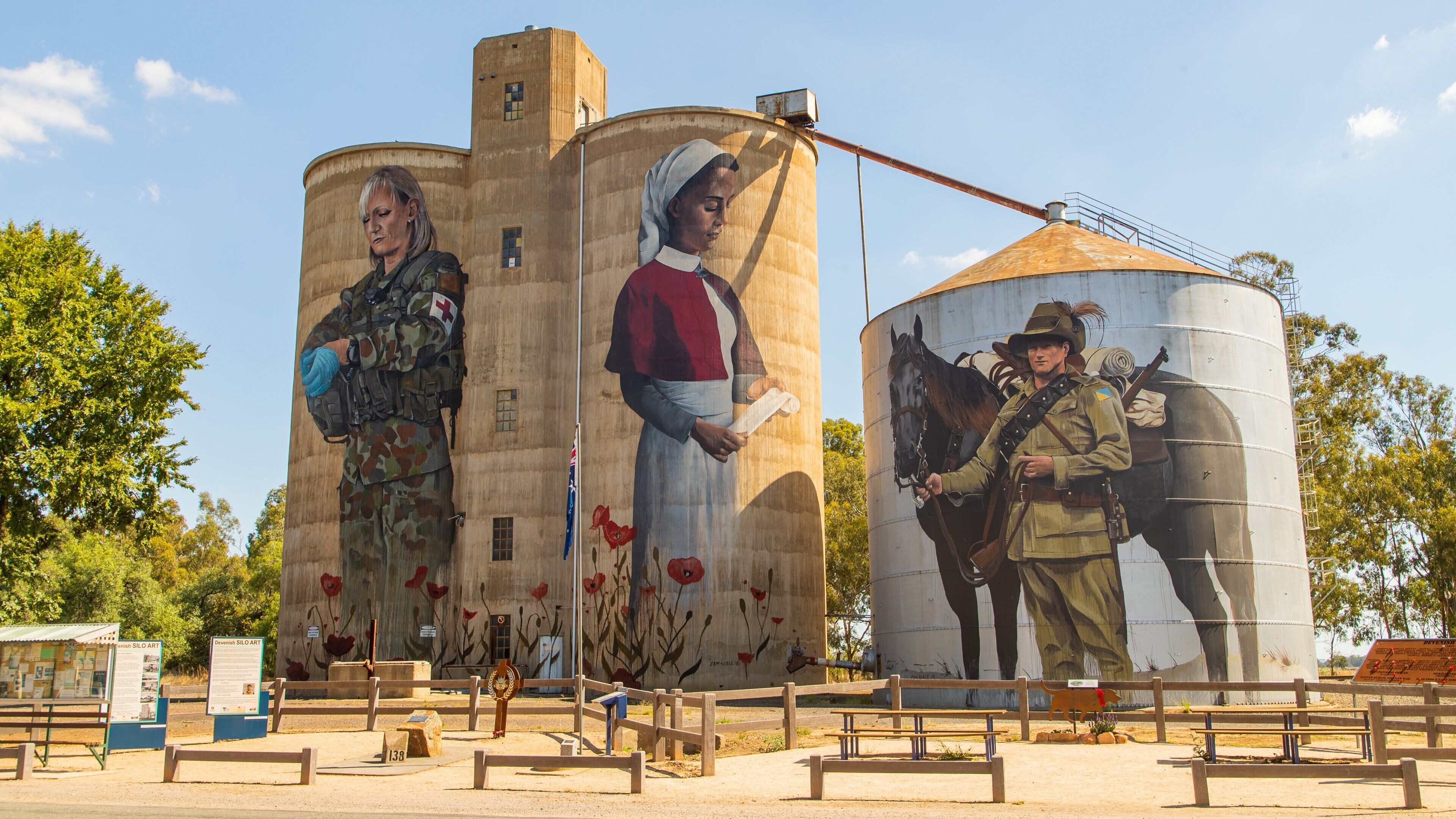 A mural on grain silos depicting historical figures and a soldier with a horse.