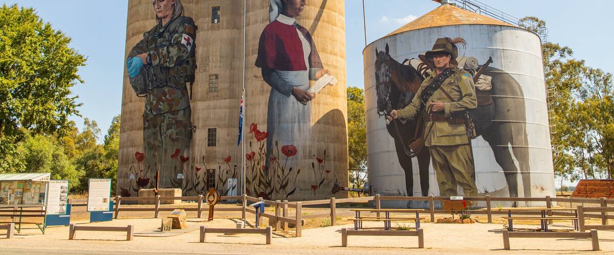 A mural on grain silos depicting historical figures and a soldier with a horse.