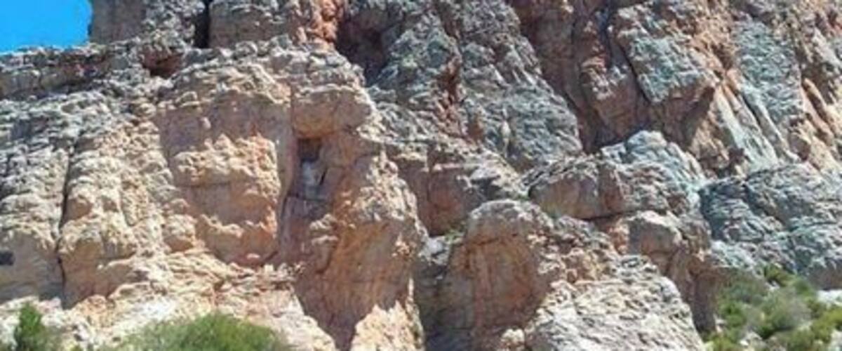 A large rock formation with a clear blue sky in the background.