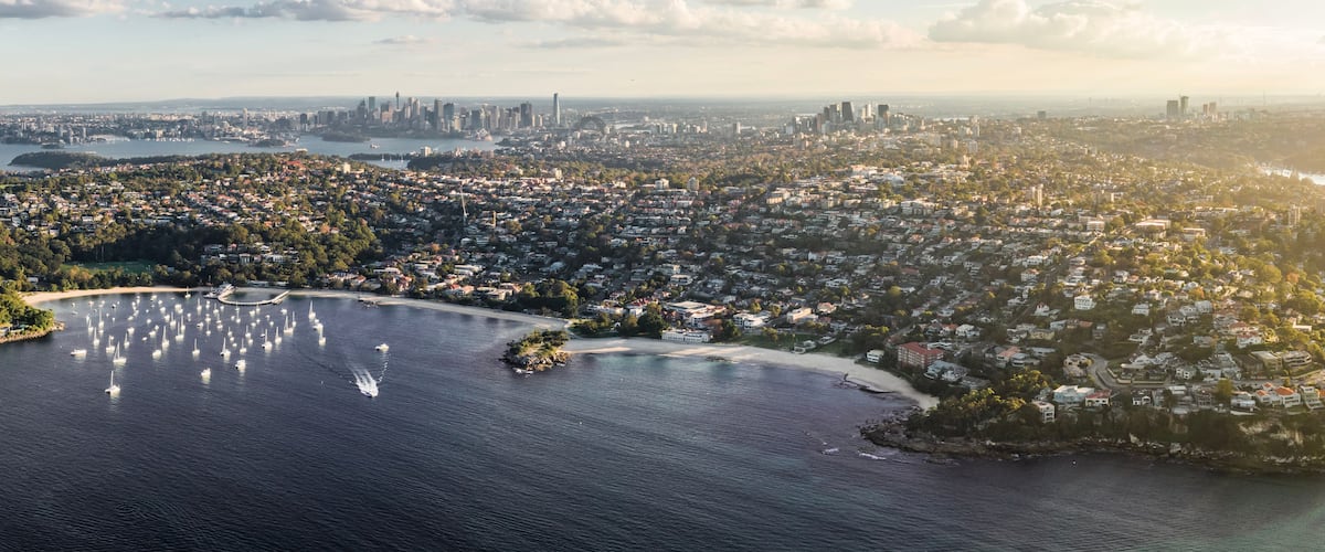 A coastal cityscape with a marina, residential areas, and a distant skyline.