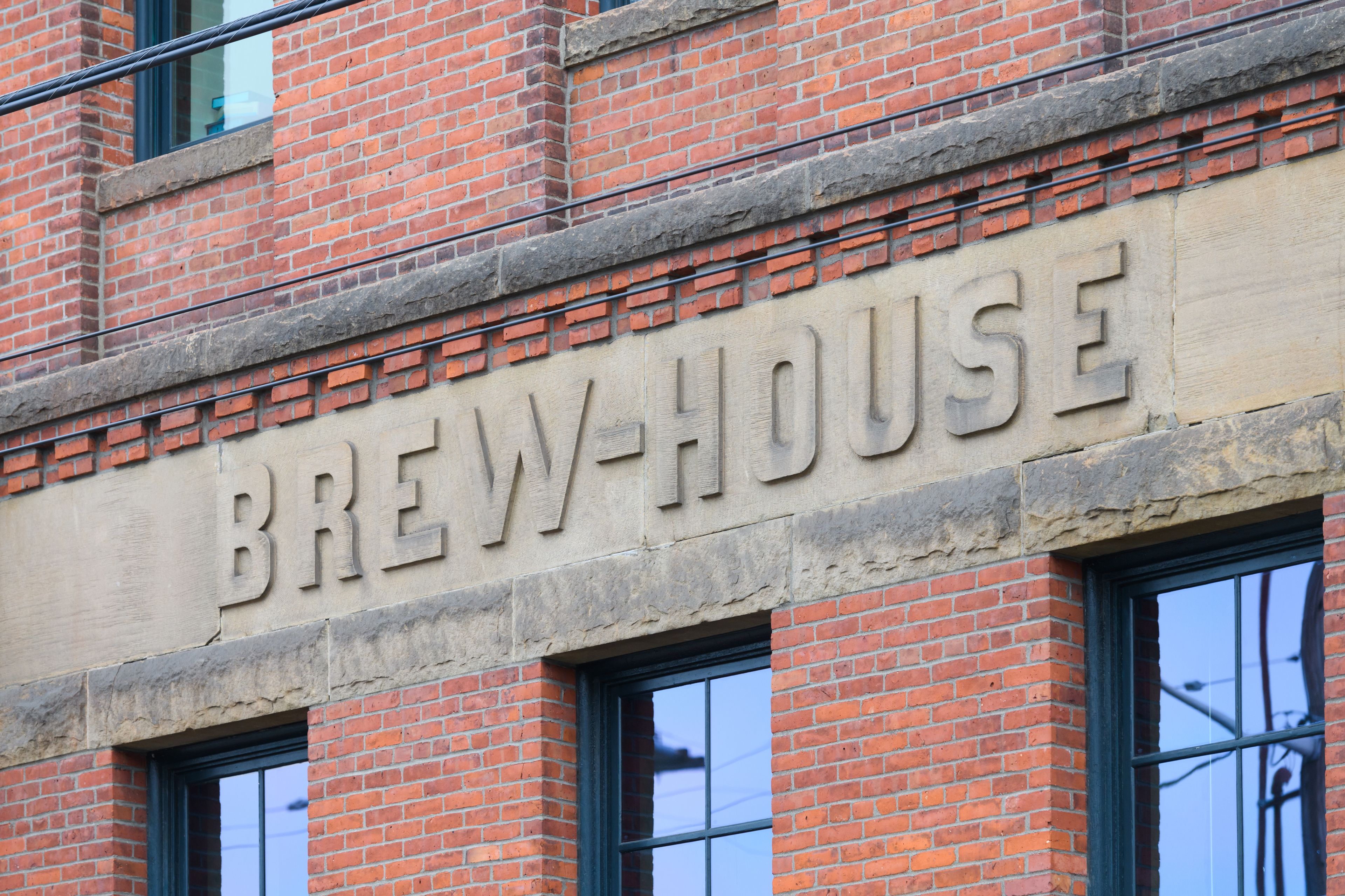 A brick building with the words 'BREW-HOUSE' carved into the stone facade.
