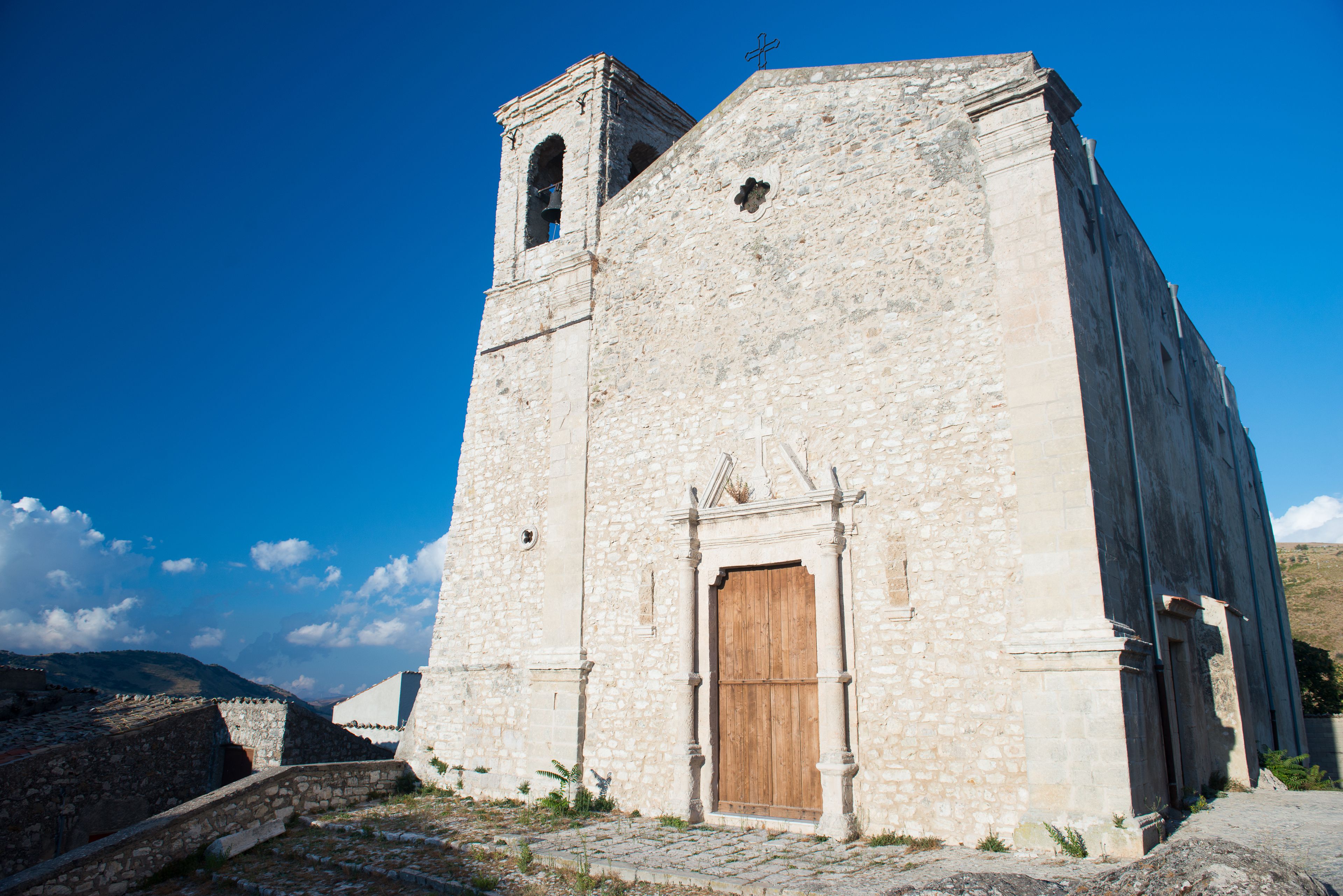 Una iglesia de piedra con puerta de madera y un campanario.