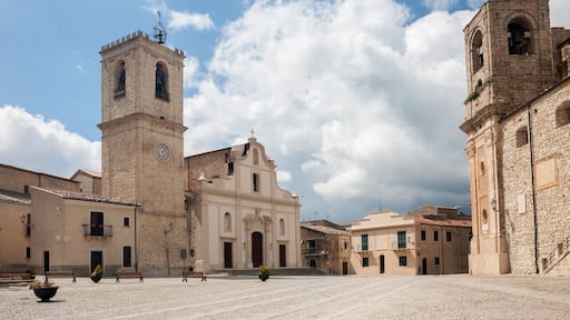 A historic square with a prominent church featuring a bell tower and a clock, surrounded by traditional buildings.