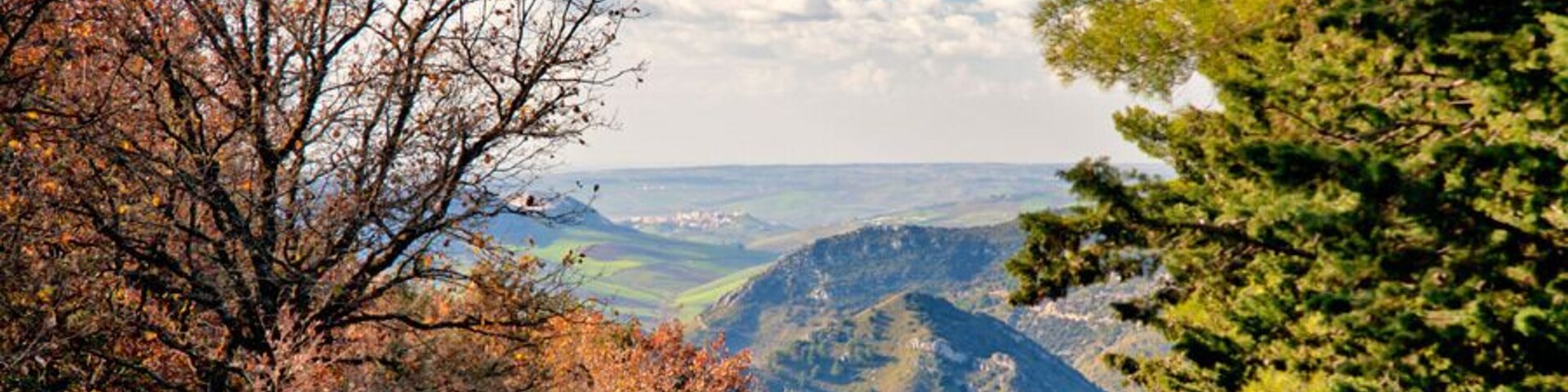 Paisaje montañoso con follaje otoñal, cielo despejado y valles lejanos.